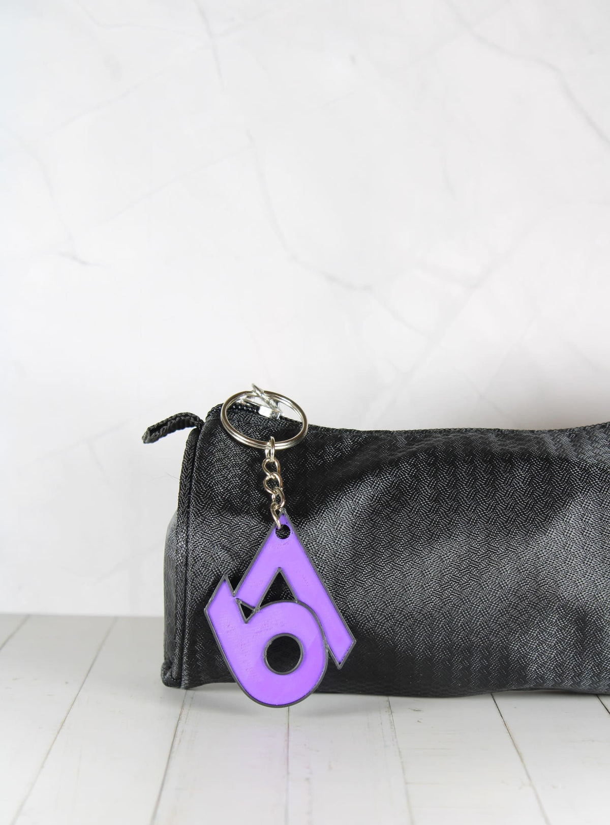 Porte-clé 67 violet et noir accroché à une trousse