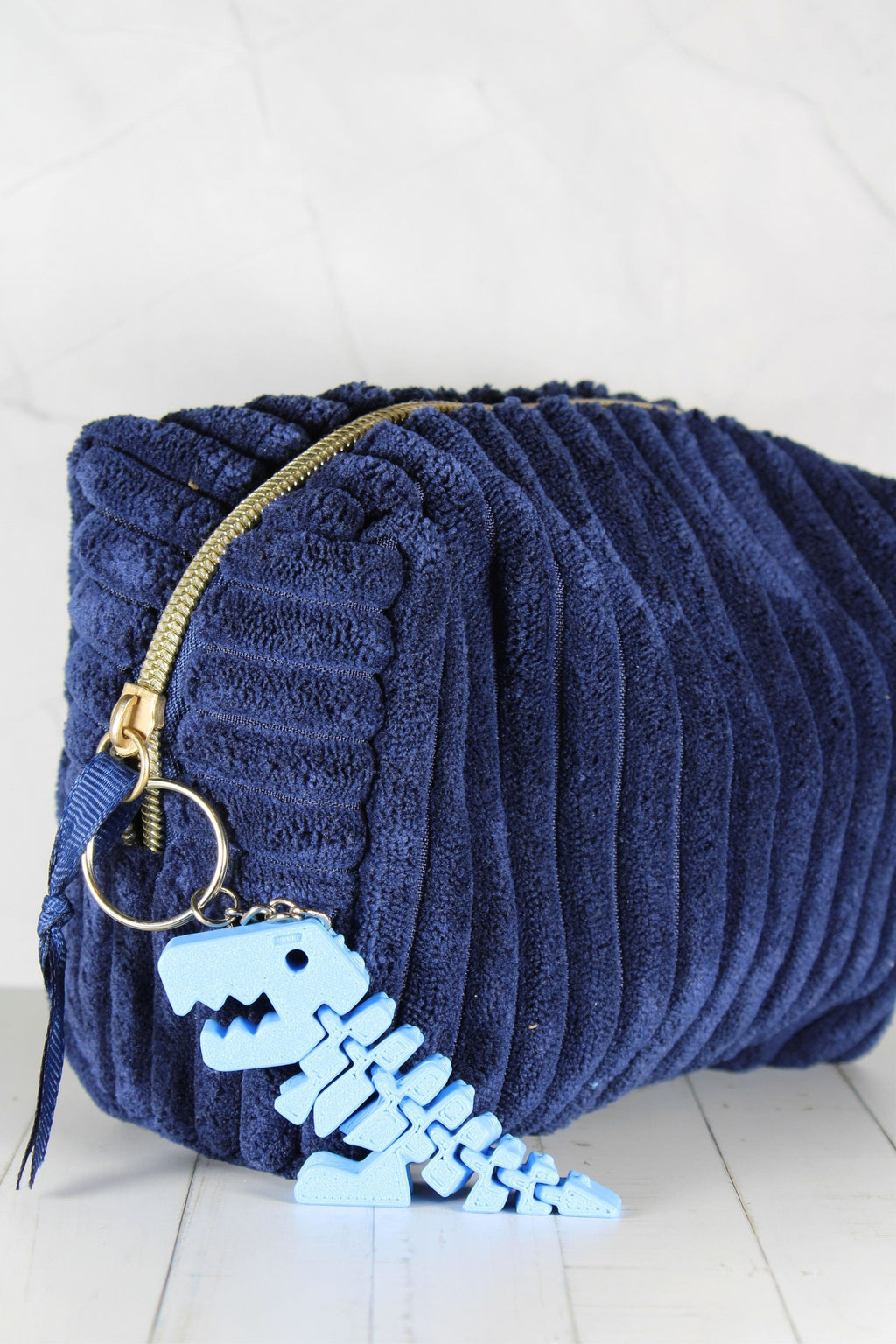 Porte-clé dinosaure bleu accroché à une trousse