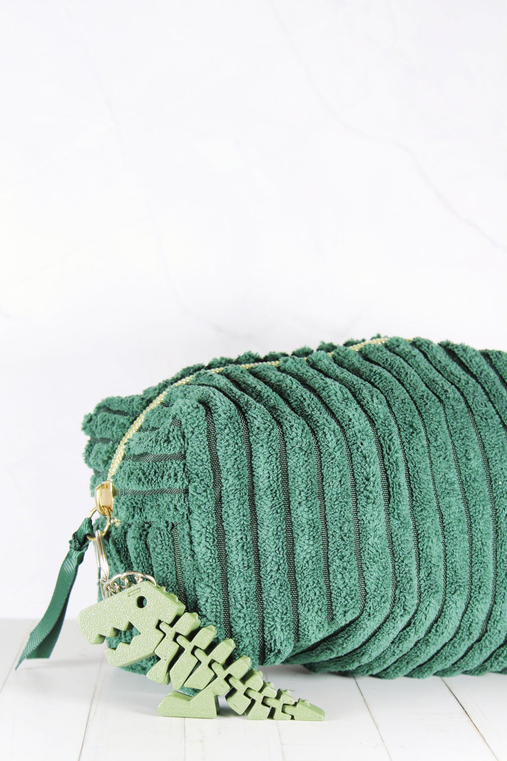 Porte-clé dinosaure vert accroché à une trousse