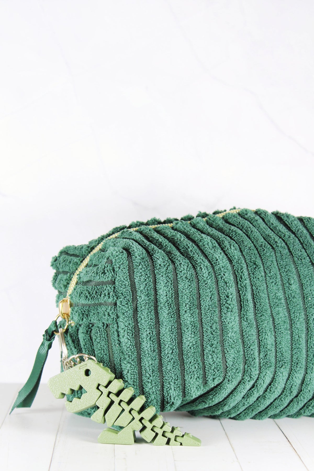 Porte-clé dinosaure vert accroché à une trousse