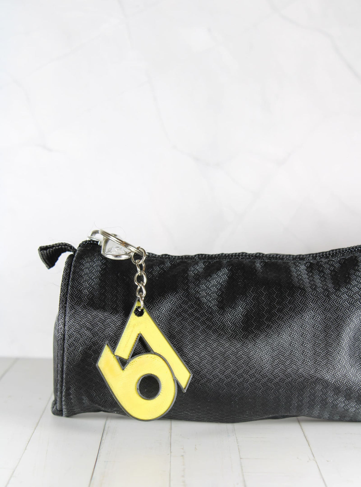 Porte-clé 67 jaune et noir accroché à une trousse
