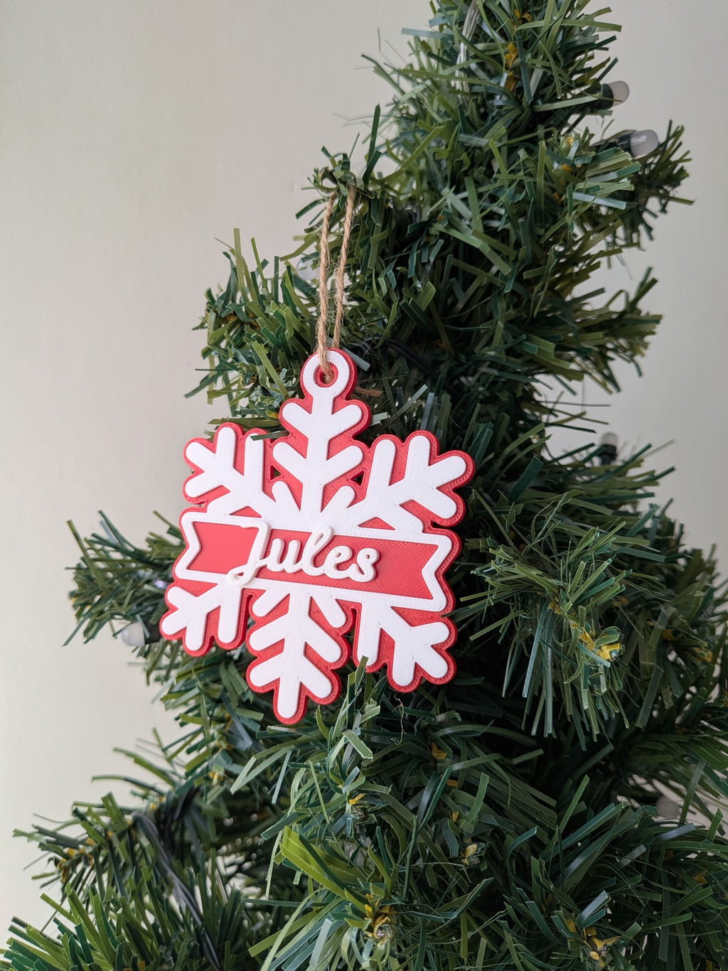 Ornement de Noël rouge et blanc en forme de flocon avec prénom Jules en relief et cordelette de suspension.