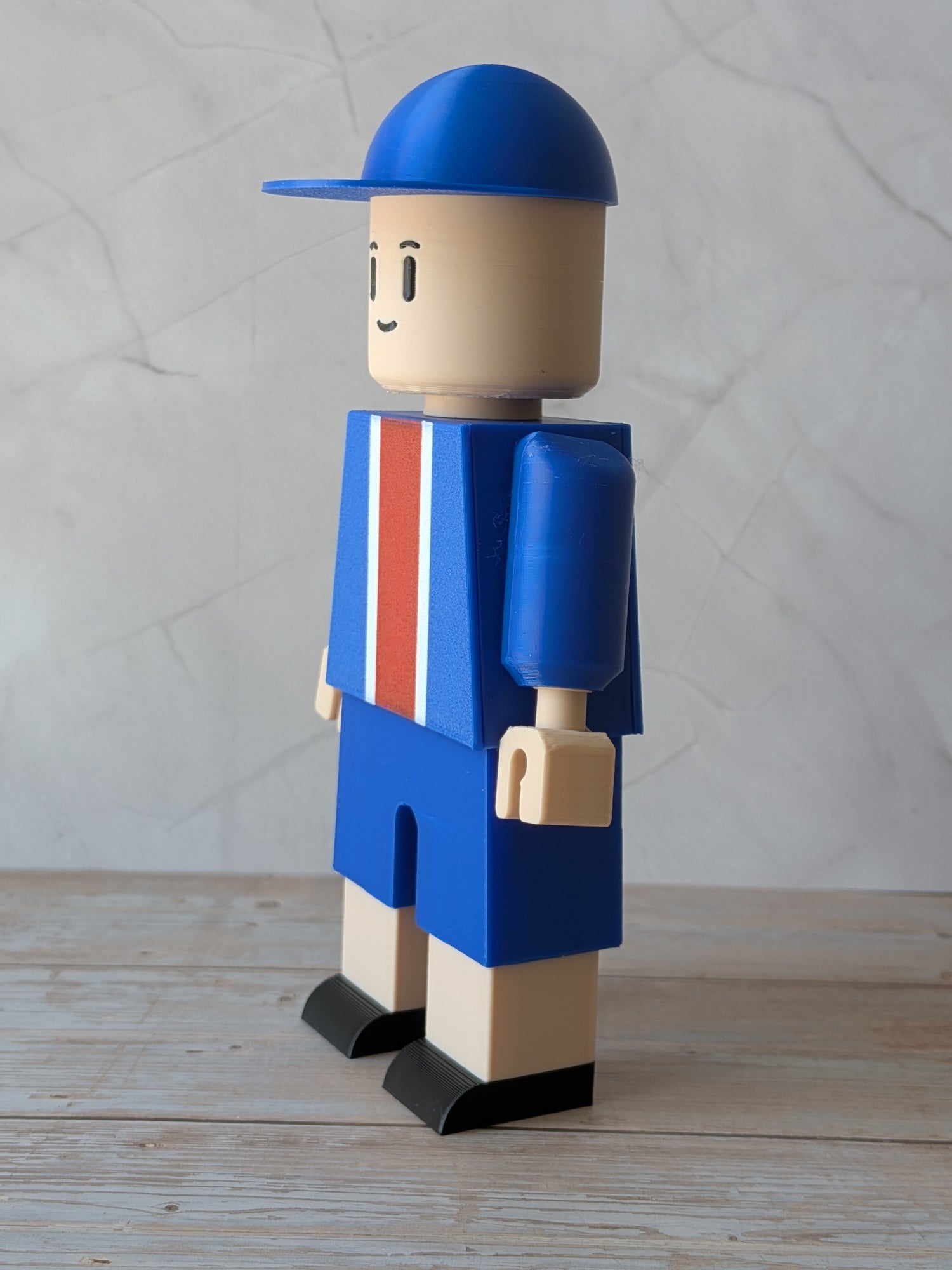 Figurine de supporter de Paris vue de profil avec casquette bleue et bras mobiles
