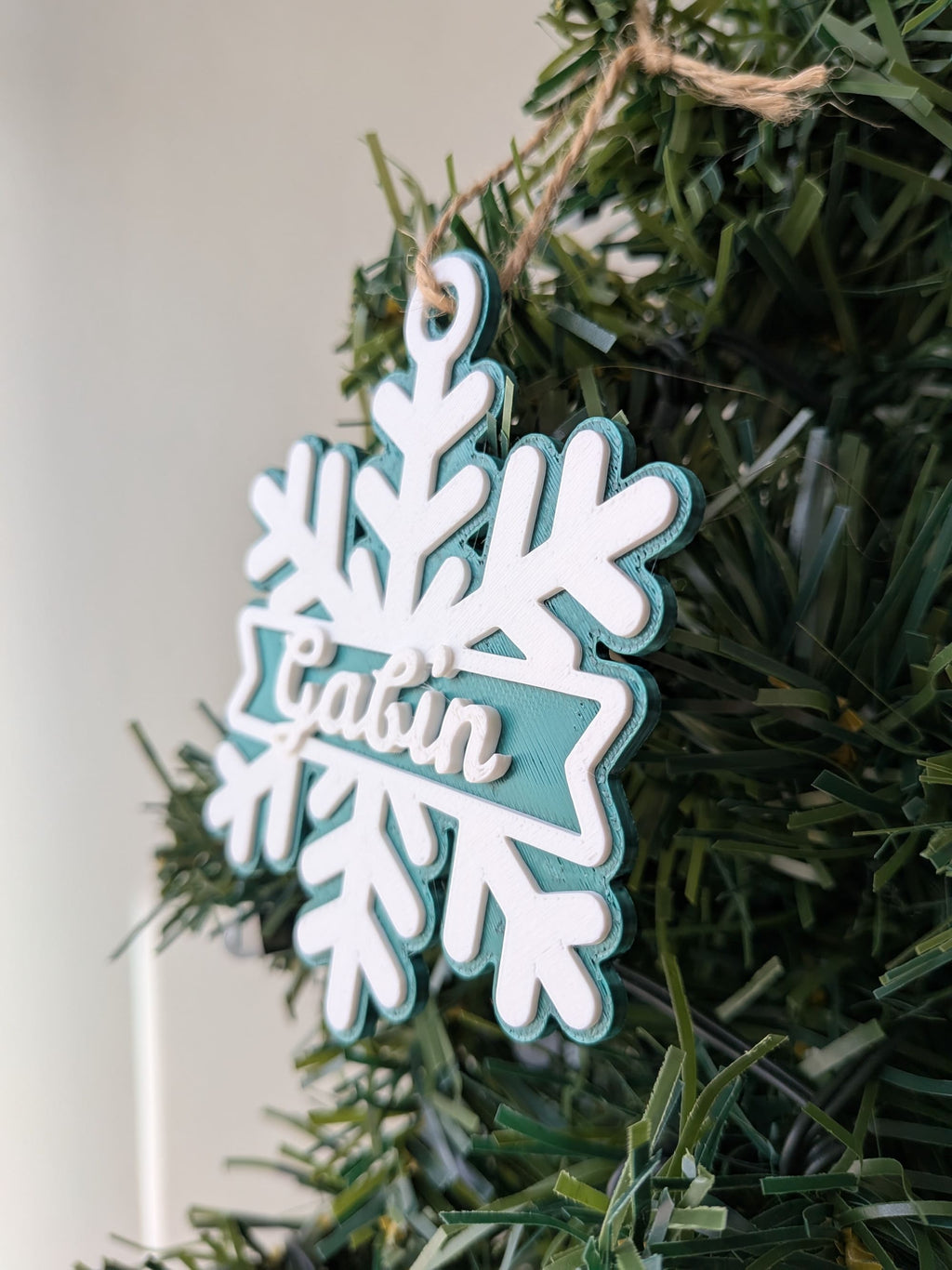 Gros plan de profil d'un flocon de Noël vert personnalisé avec prénom Gabin montrant les trois niveaux de relief imprimés en 3D.