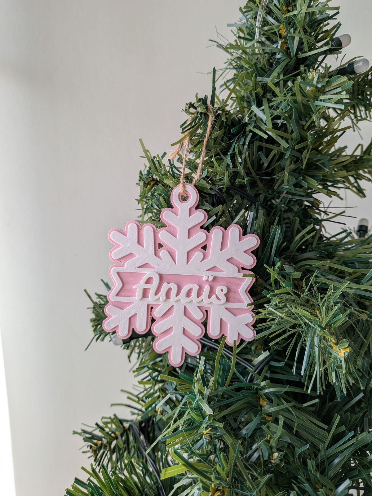 Décoration de Noël rose et blanche en forme de flocon de neige avec prénom Anaïs personnalisé.